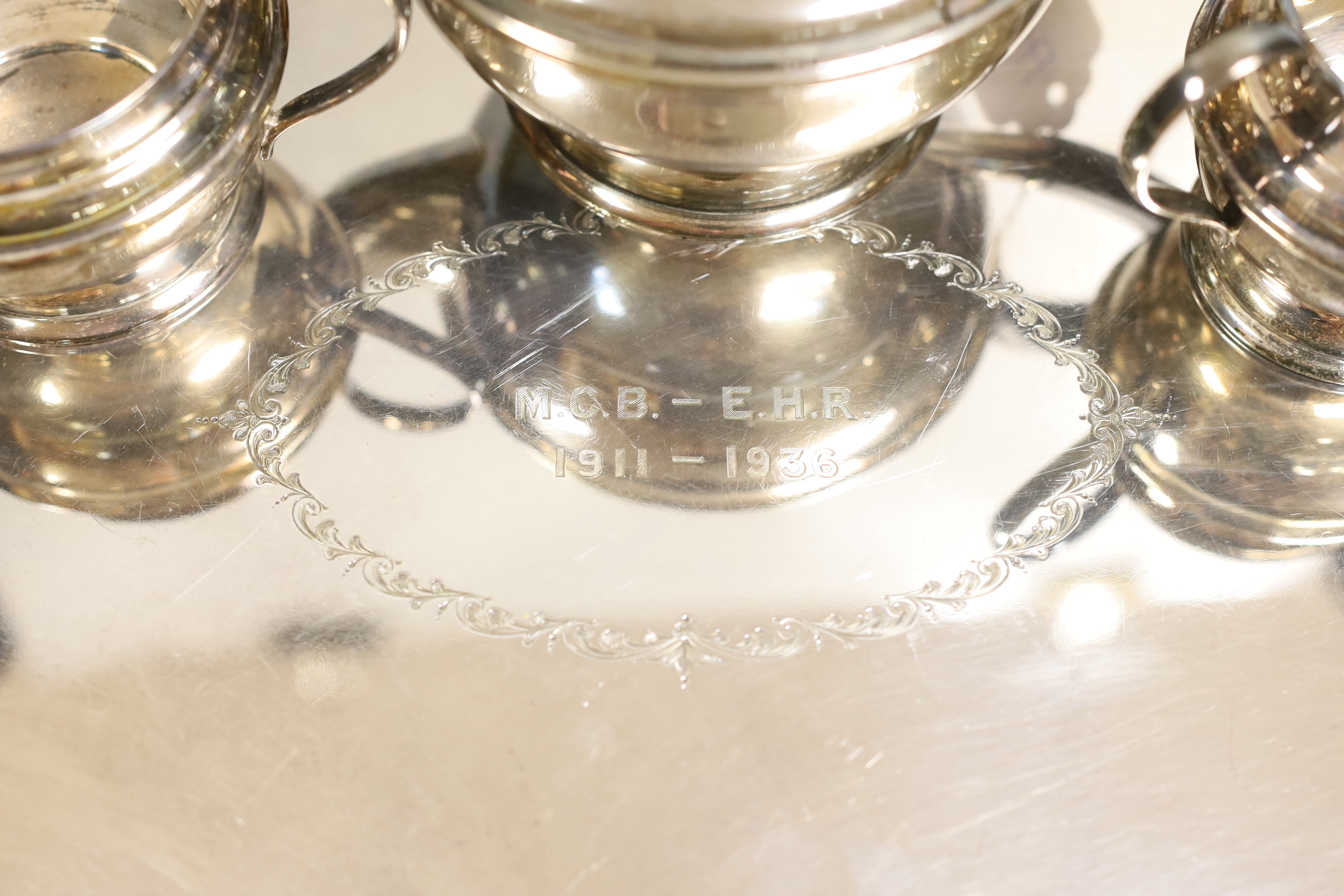 A George VI silver three-piece tea set, with engraved inscription, W.F. Mitchell, Birmingham, 1936, gross weight 22oz and a plated two handled tea tray, 49.3cm.